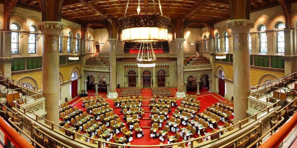 Interior of the New York State Assembly Chamber in Albany with rows of empty desks