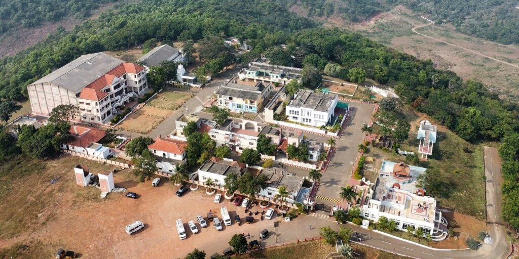 Aerial view of a film studio complex surrounded by green hills and forested landscape