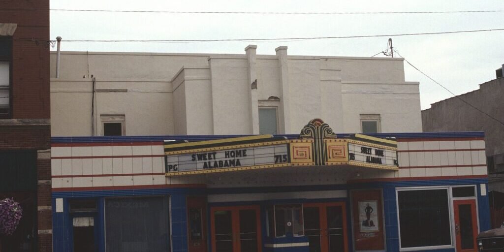 Movie theater exterior with marquee and box office window on a street corner