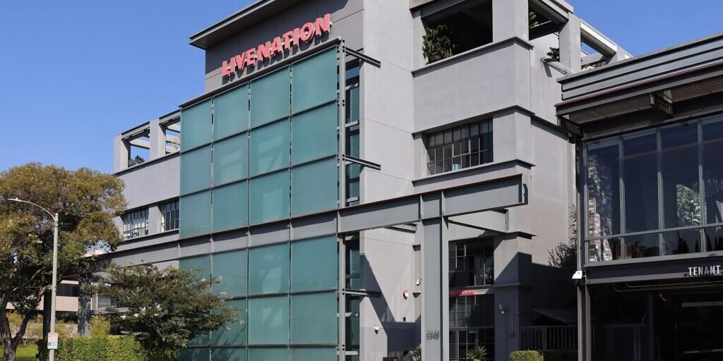 Multi-storey grey office building with a red Live Nation sign on its glass facade, beside a street in Beverly Hills.