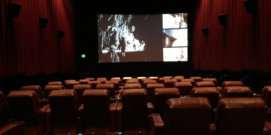 Empty movie theater auditorium with rows of brown leather recliners