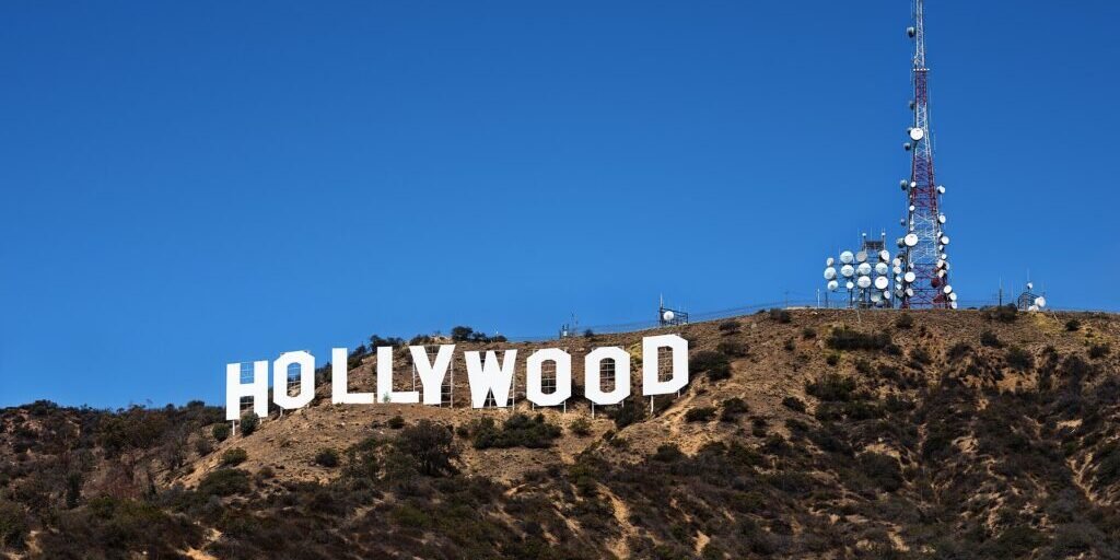 The Hollywood Sign on a hillside with transmission tower and clear blue sky